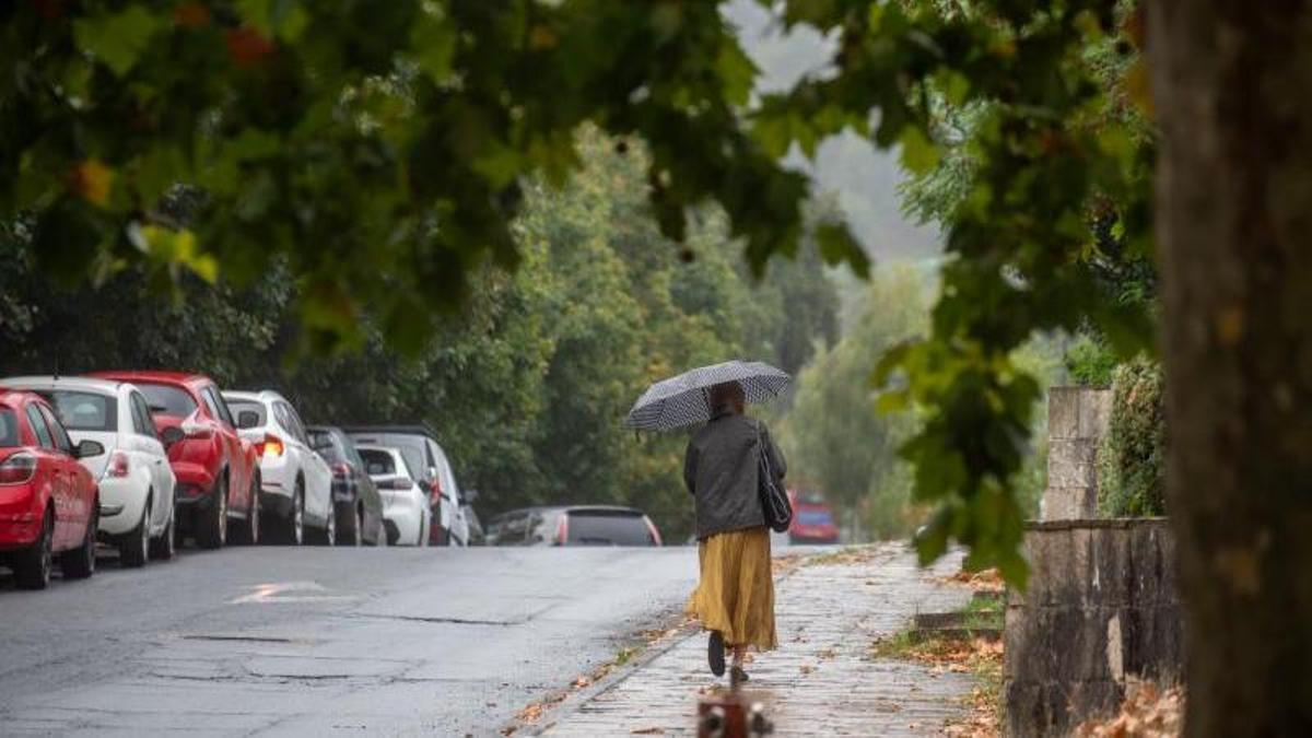Una mujer camina con un paraguas en A Coruña.