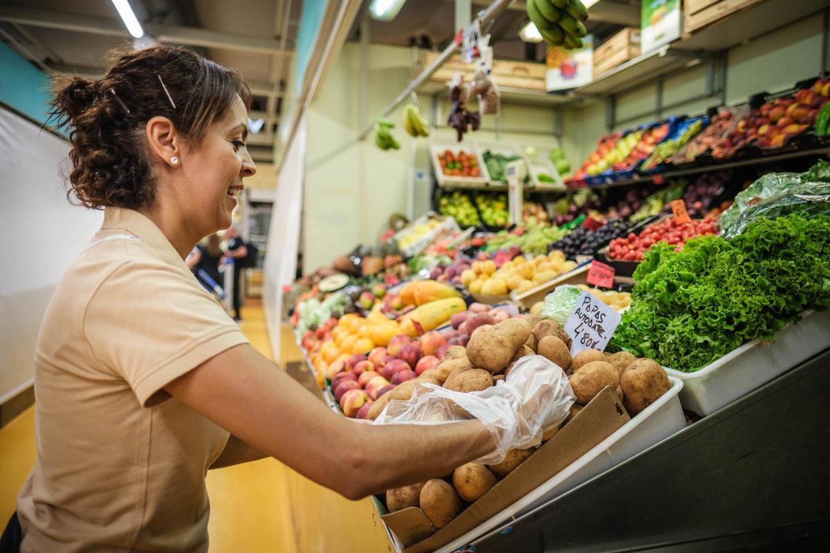 Una mujer coloca las frutas y verduras del día en su tienda.