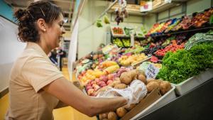 Una mujer coloca las frutas y verduras del día en su tienda.