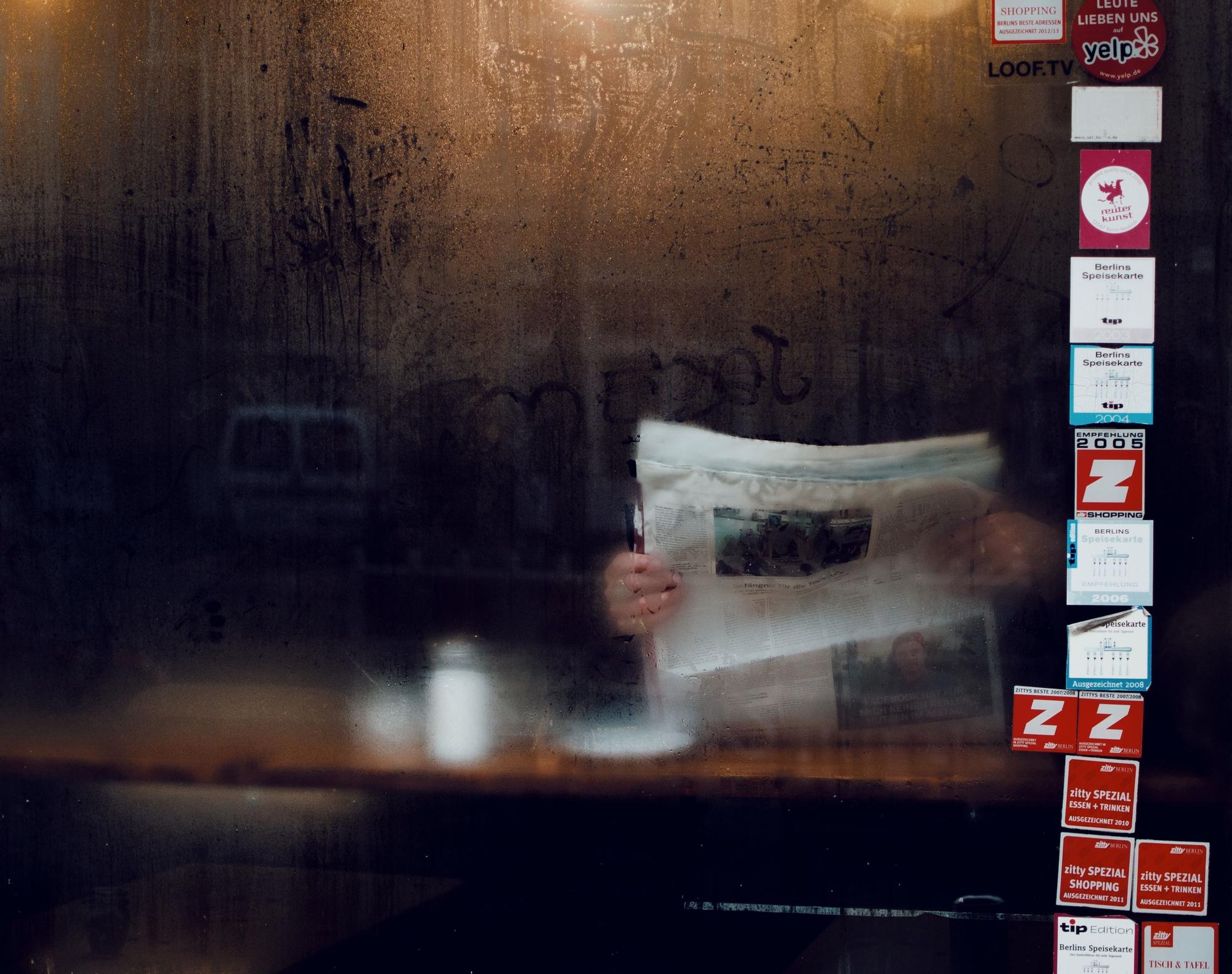 Un hombre leyendo un periódico en un local.