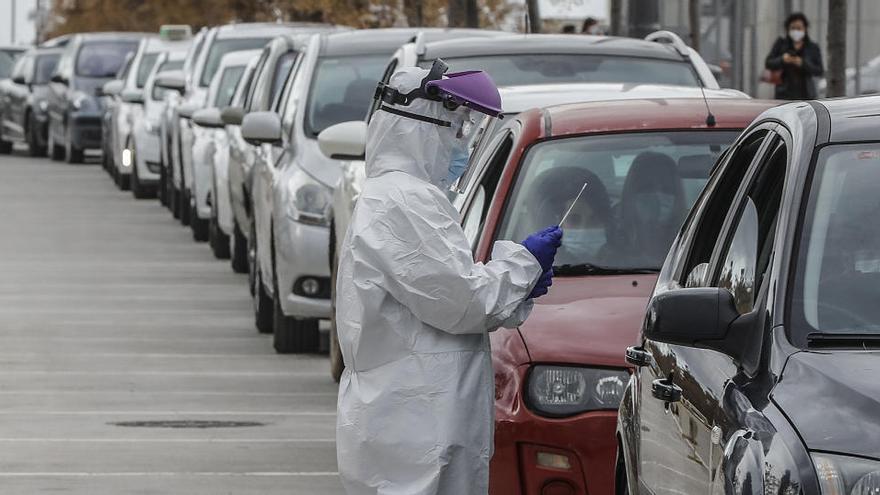 Un sanitario realiza una prueba PCR a una persona desde su vehículo en Valencia