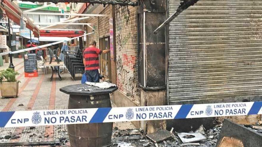 El dueño de un bar abre el sábado la persiana metálica tras el incendio intencionado en la galería comercial Los Geranios.