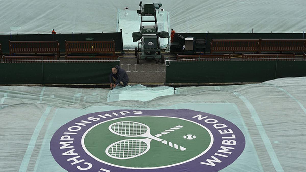 Encargados de las pistas cubren una para preservarla de la lluvia, en los preparativos del torneo de Wimbledon.