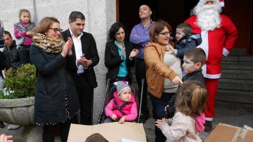 Alma observa la entrega desde su sillita, junto a su madre, hermanos, alcaldesa y Papá Noel.  // E.G.