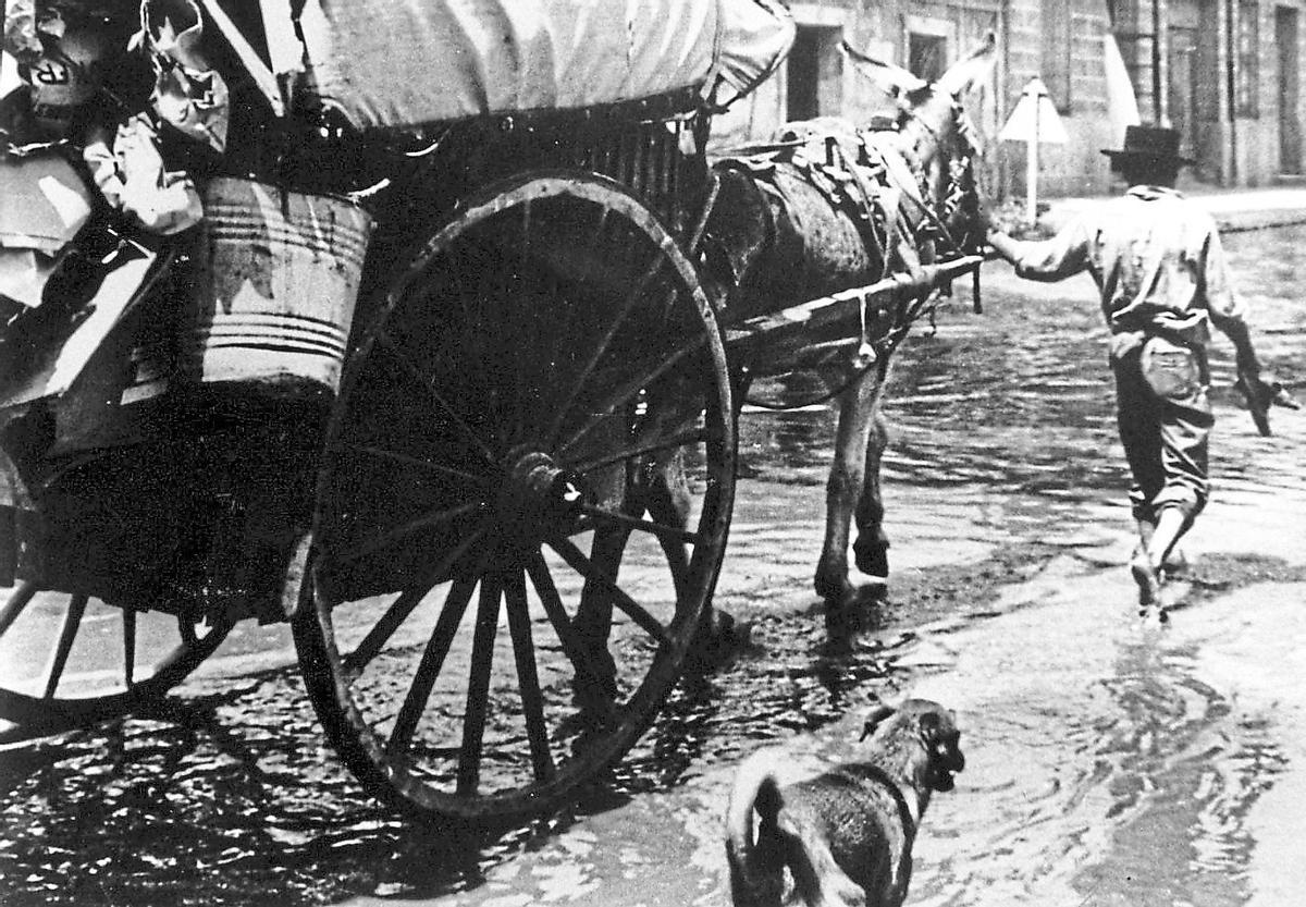 Un hombre acompaña a un caballo que tira un carro.