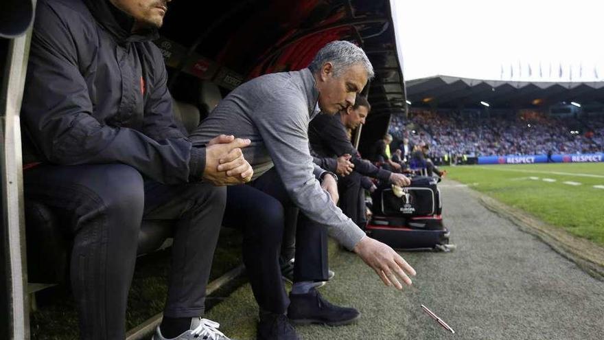 Mourinho, junto a Rui Faria, deja su bloc de notas delante del banquillo. // Carl Recine
