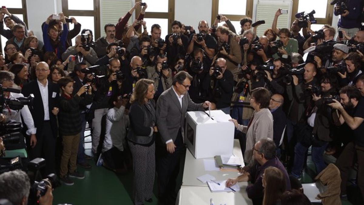 Artur Mas vota junto a su esposa, rodeado de cámaras y fotógrafos.