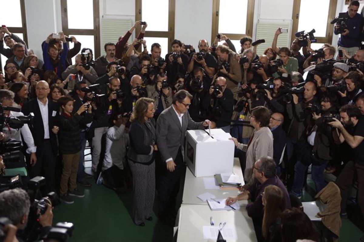 Artur Mas vota al costat de la seva dona, envoltat de càmeres i fotògrafs.