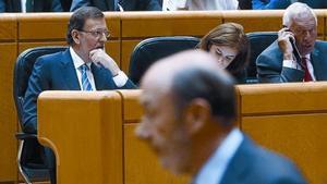 Rajoy mira a la tribuna mientras Pérez Rubalcaba vuelve a su escaño tras su primera en el pleno de ayer.