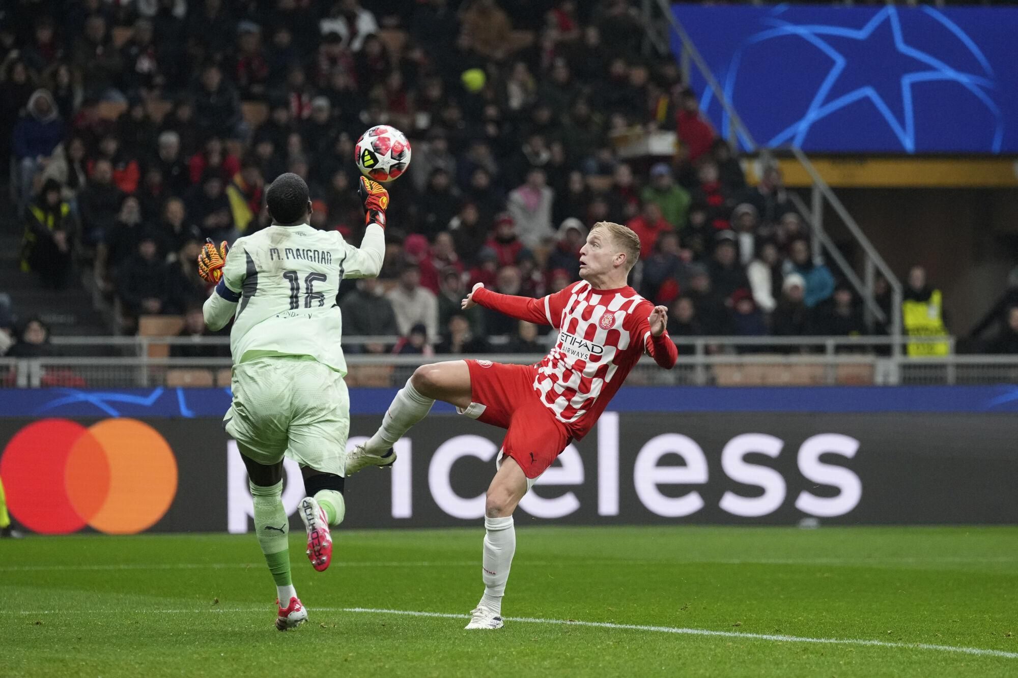 Girona's Donny van de Beek, left, challenges AC Milan's goalkeeper Mike Maignan during the Champions League opening phase soccer match between AC Milan and Girona at the San Siro stadium in Milan, Italy, Wednesday, Jan. 22, 2025. (AP Photo/Antonio Calanni). EDITORIAL USE ONLY/ONLY ITALY AND SPAIN