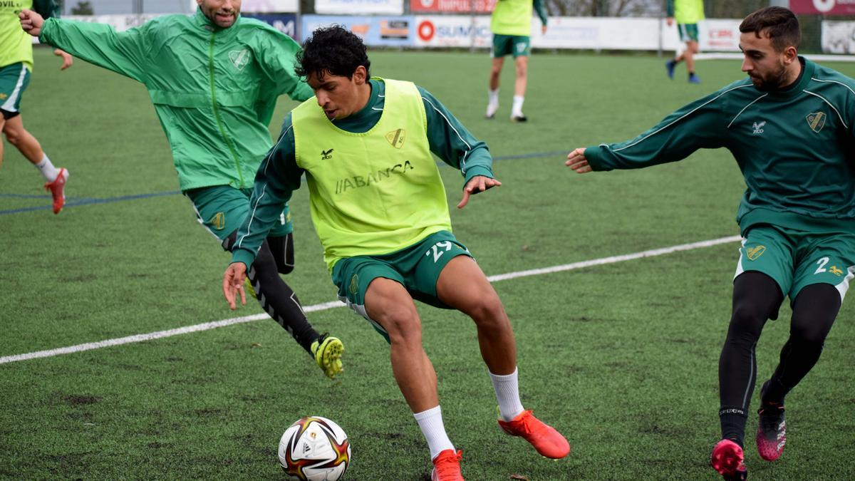 Manu y Chiqui, del Coruxo, presionan a Johan en un entrenamiento en Fragoselo.