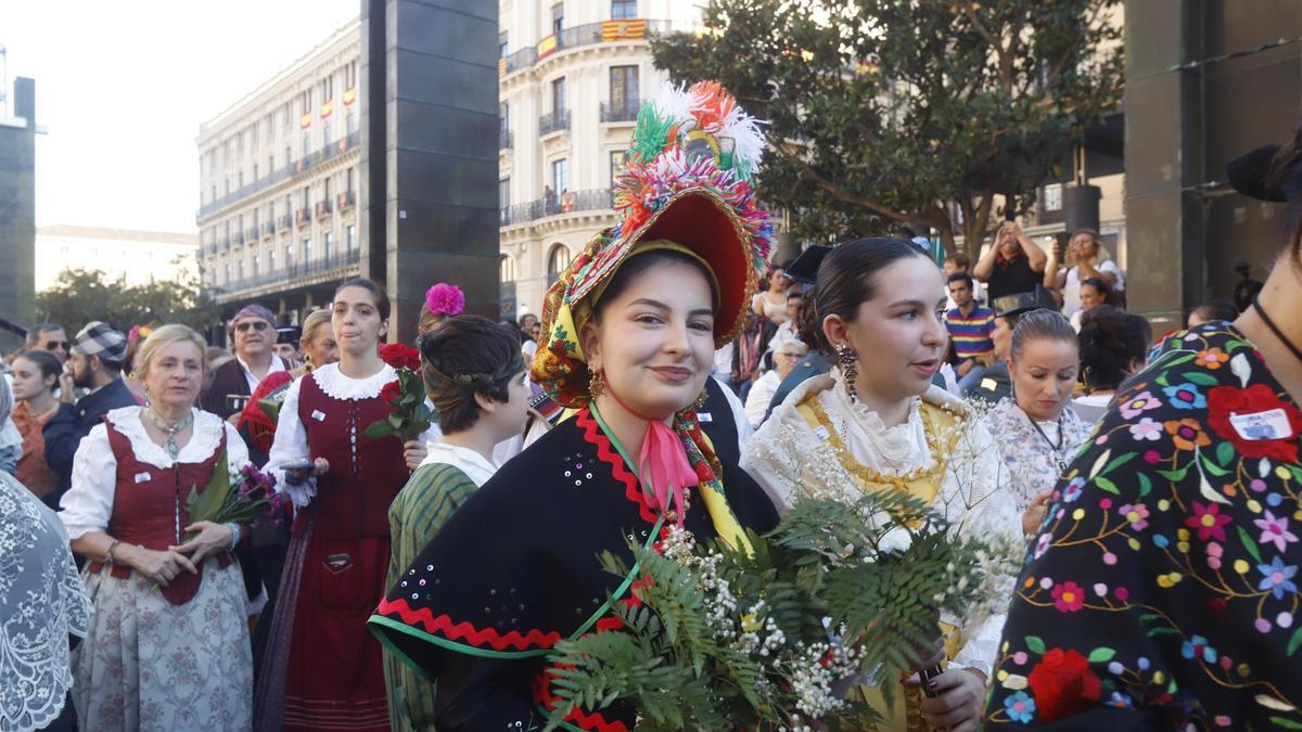 Una mujer vestida con su traje tradicional lleva las flores a la Virgen del Pilar