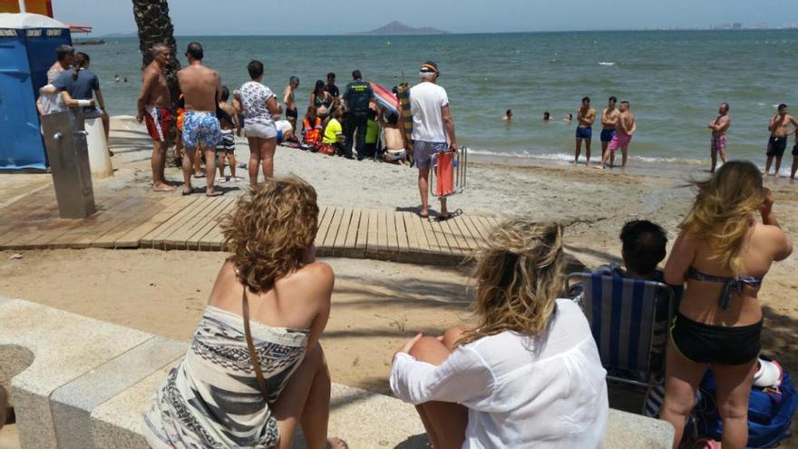 La gente mira cómo intentan reanimar al hombre.