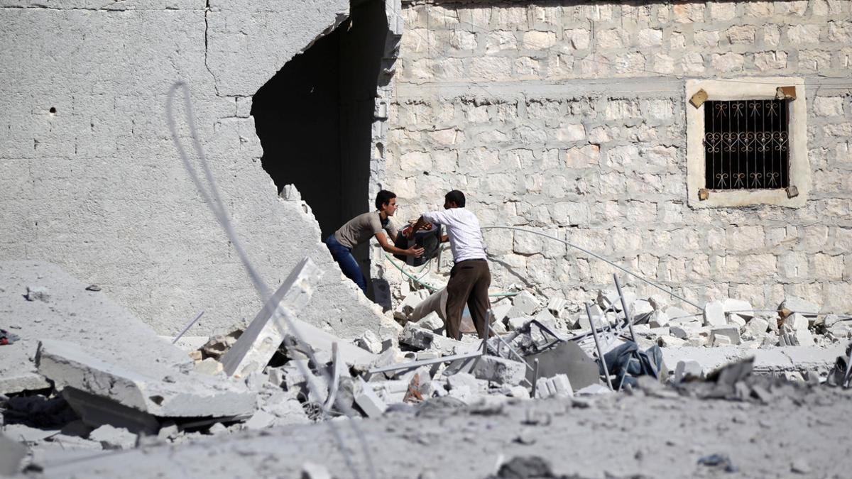 Men carry their belongings from their damaged home near Guzhe village, northern Aleppo countryside