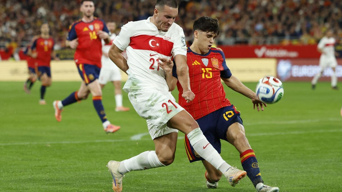 SEVILLA, 18/11/2025.- El delantero de Turquía, Deniz Gül (i), disputa el balón ante el defensa de la selección española, Marc Cubarsí, durante el encuentro correspondiente a la fase de clasificación para el Mundial 2026 que disputan hoy martes España y Turquía en el estadio de La Cartuja, en Sevilla. EFE / Julio Muñoz.