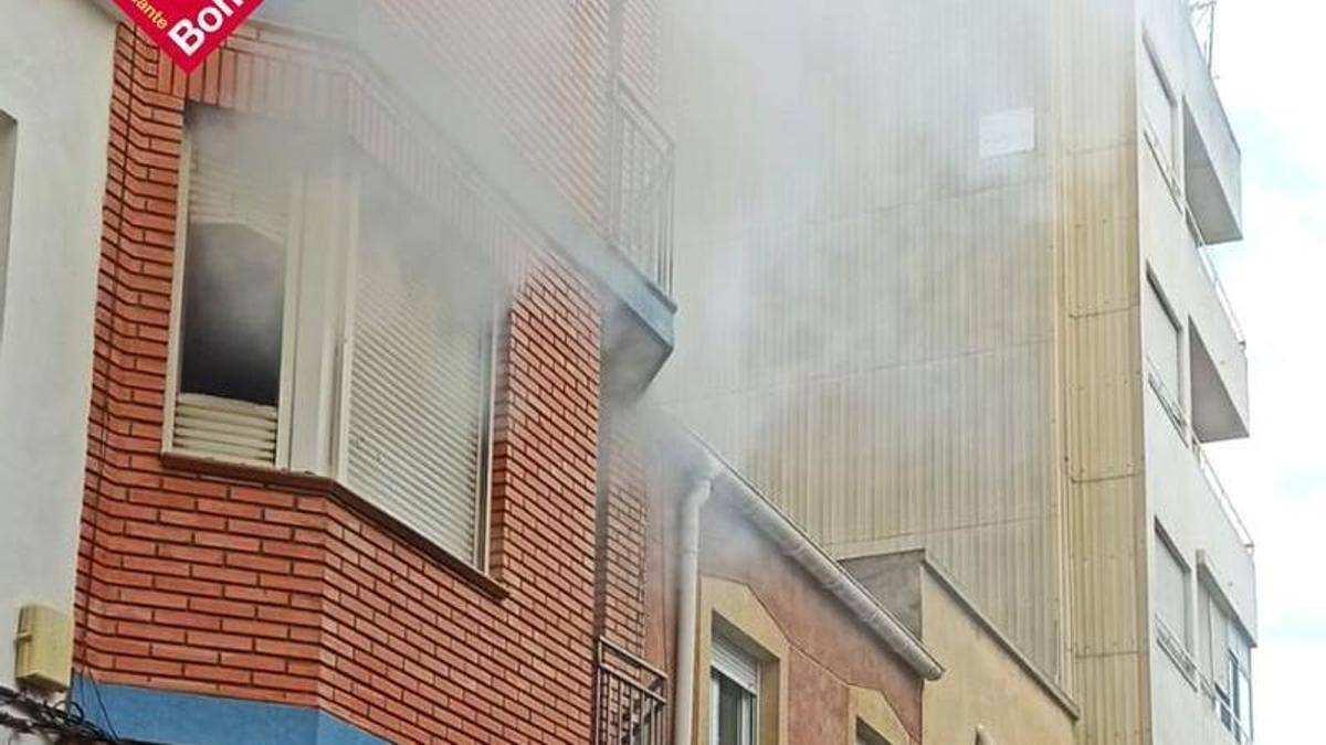 Humo saliendo por la ventana de la vivienda afectada por el incendio en Villena.