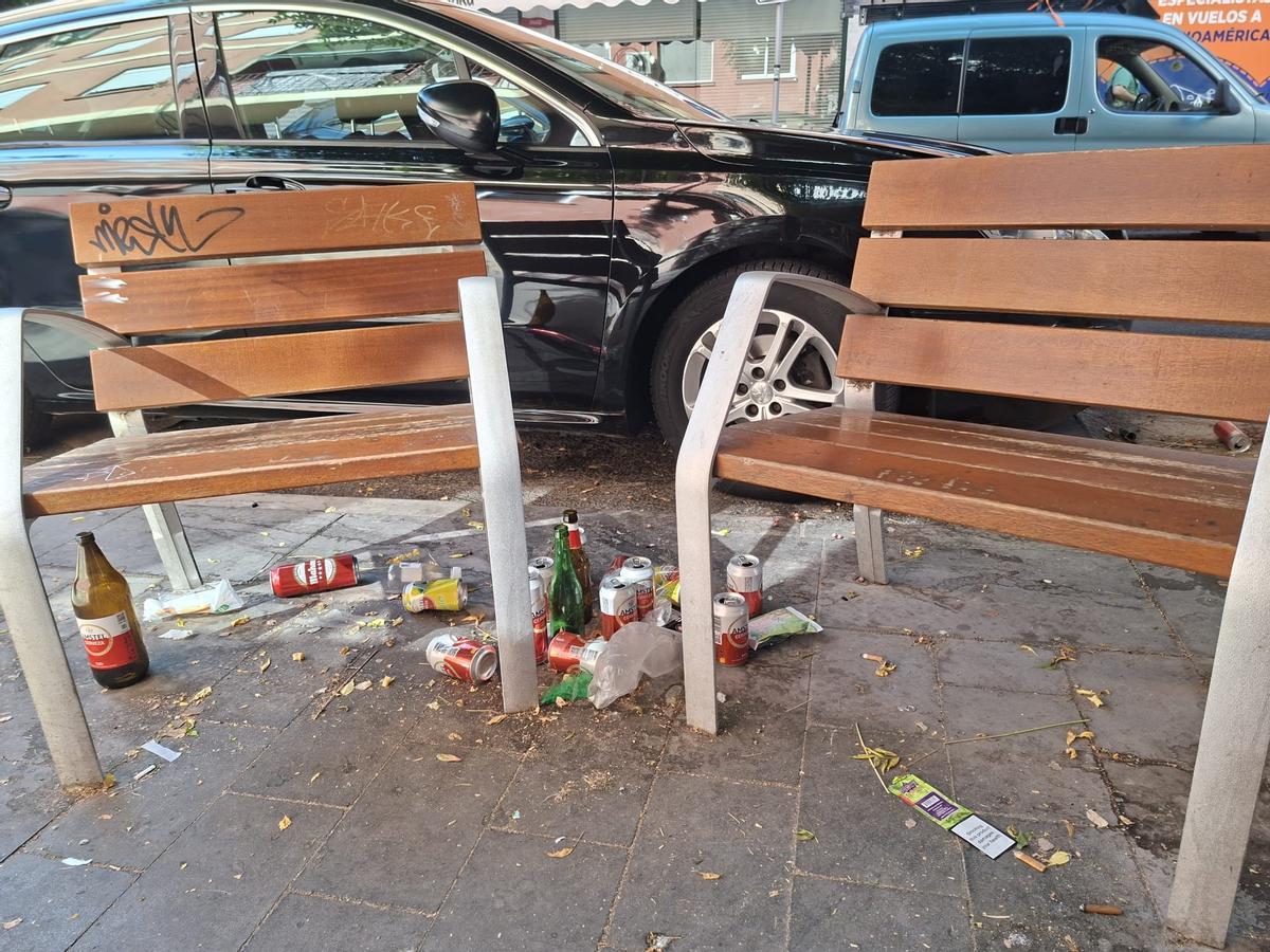 Restos de latas, botellas y comida acumulados alrededor de los bancos del barrio