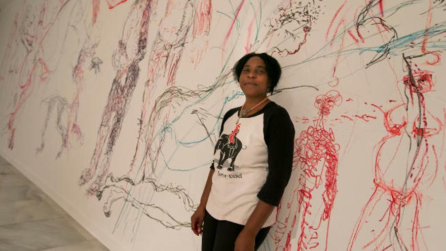 La artista Pèlagie Gbaguidi, junto a su mural en curso.