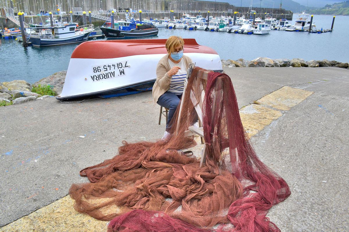 Teté Costales cose unas redes en el puerto de Lastres.