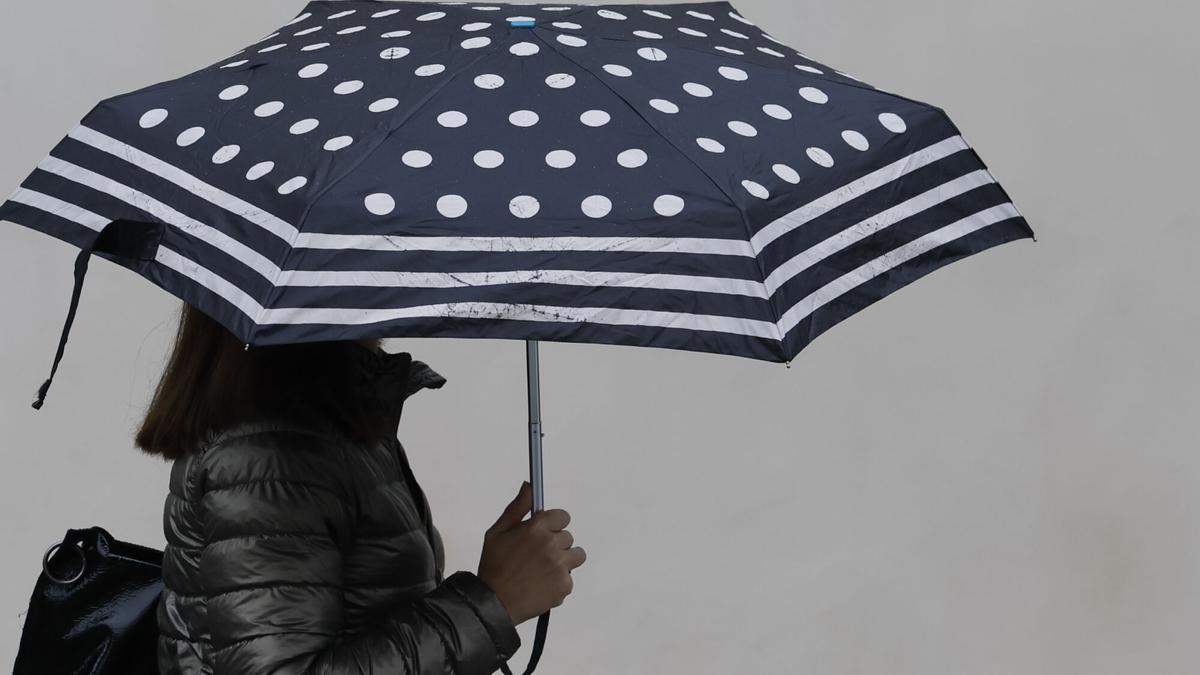 Una persona es protegeix de la pluja amb paraigua.