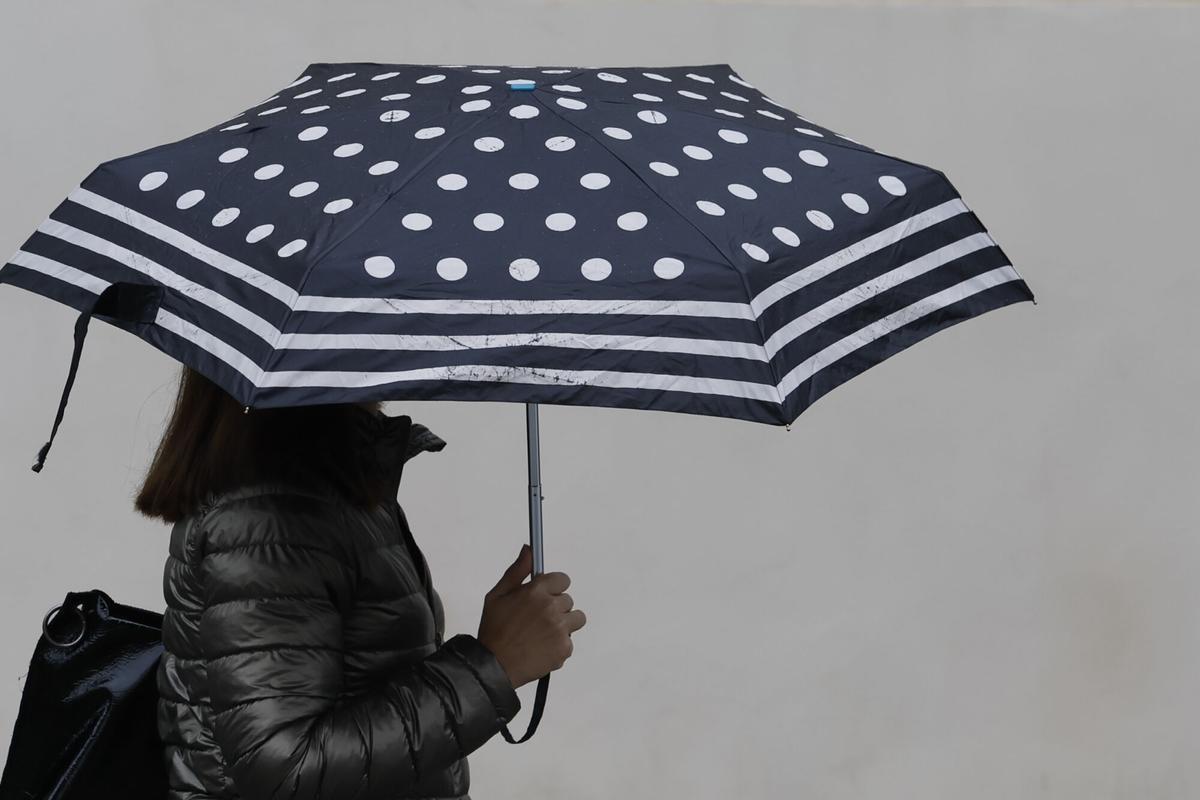 Una persona es protegeix de la pluja amb paraigua.