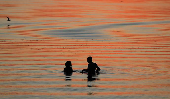 La gente disfruta la puesta de sol en un lago en las afueras de Minsk, Bielorrusia