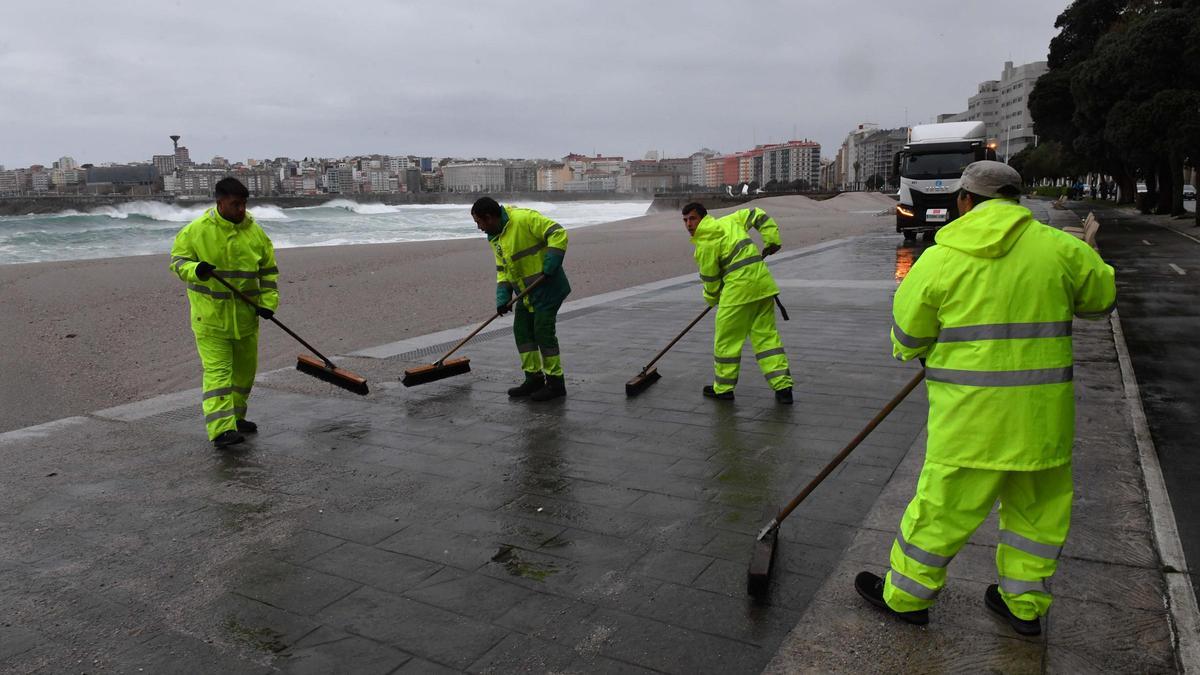 Operarios limpian la arena en el paseo marítimo.
