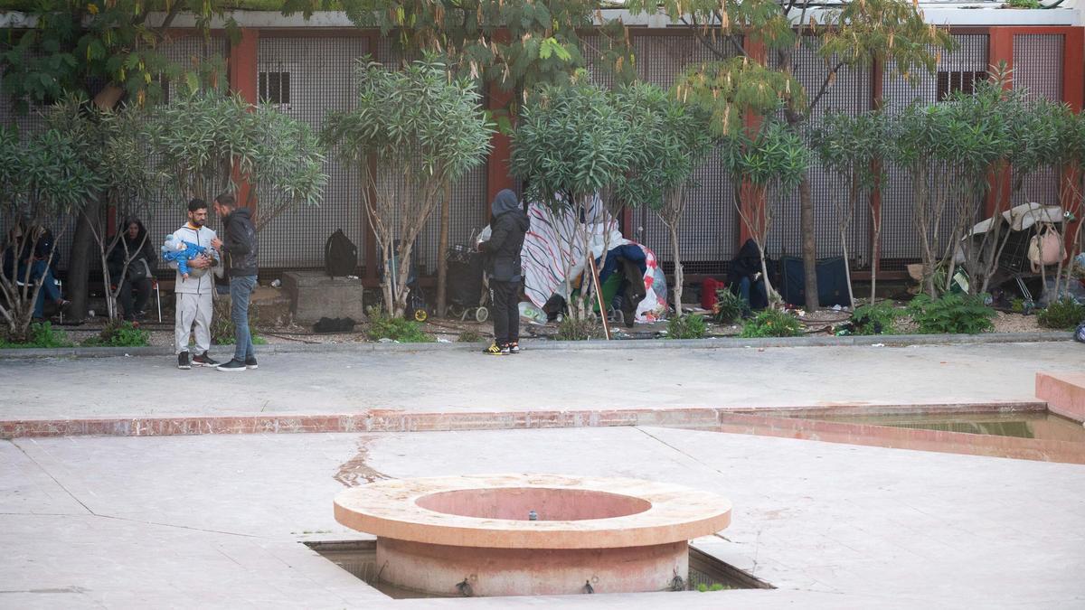 Personas sin hogar en los alrededores del albergue. A la izquierda, un hombre con un bebé en brazos.