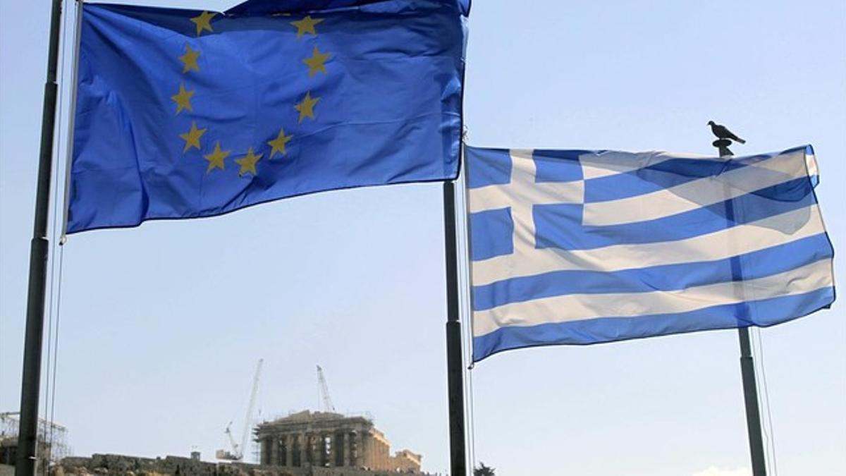 Una bandera griega y una de la UE ondean junto a la Acrópolis (al fondo), en Atenas, este martes.