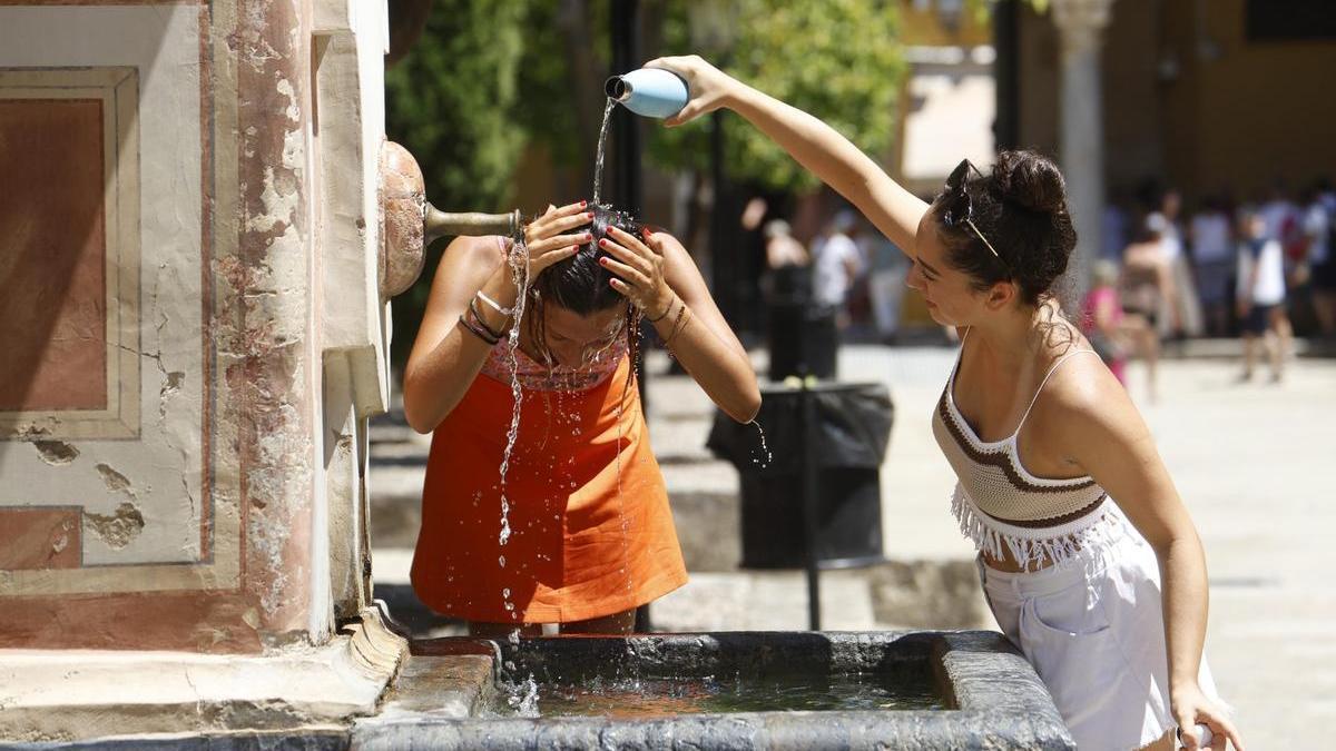 Dos mujeres se refrescan en una fuente del Patio de los Naranjos de la Mezquita Catedral de Córdoba durante una ola de calor.