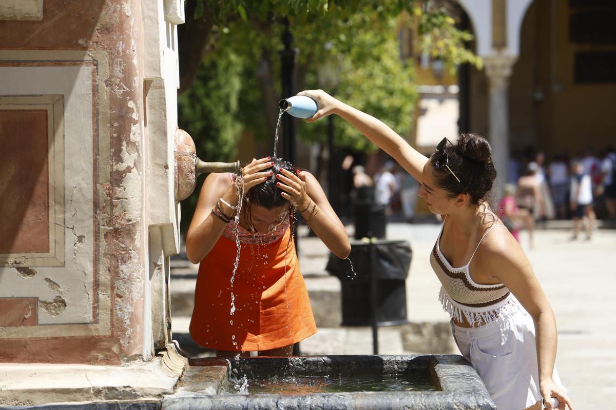 Dos mujeres se refrescan en una fuente del Patio de los Naranjos de la Mezquita Catedral de Córdoba durante una ola de calor.