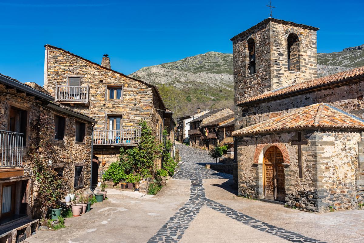 Iglesia de pueblo con casas de piedra junto a la montaña, Castilla-La Mancha