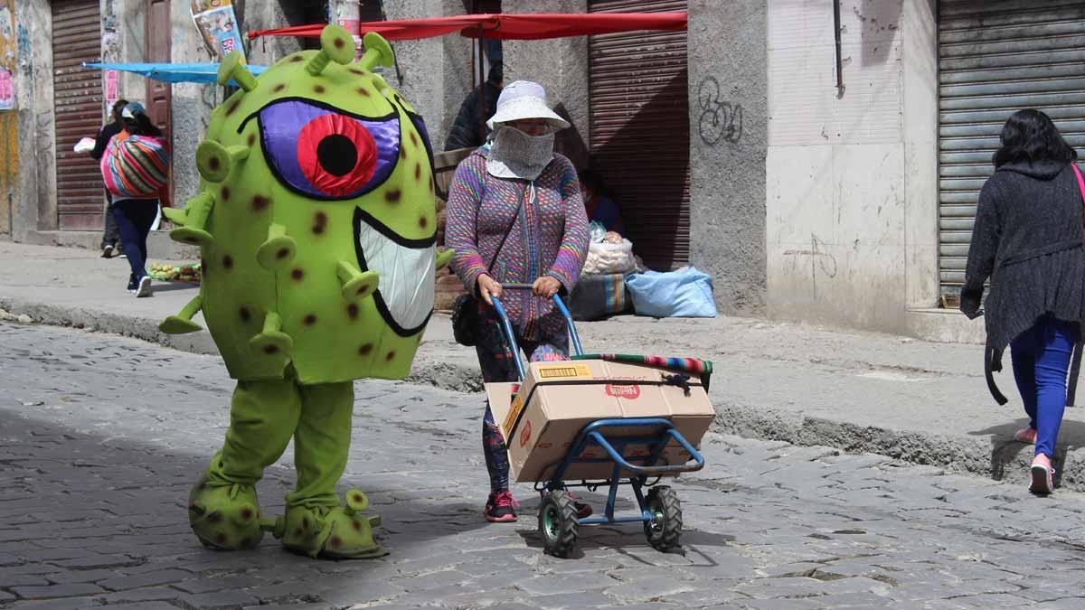 La policía de Bolivia educa a los ciudadanos con muñecos de coronavirus. En la foto, uno de los personajes se dirige a una mujer en una calle de La Paz.