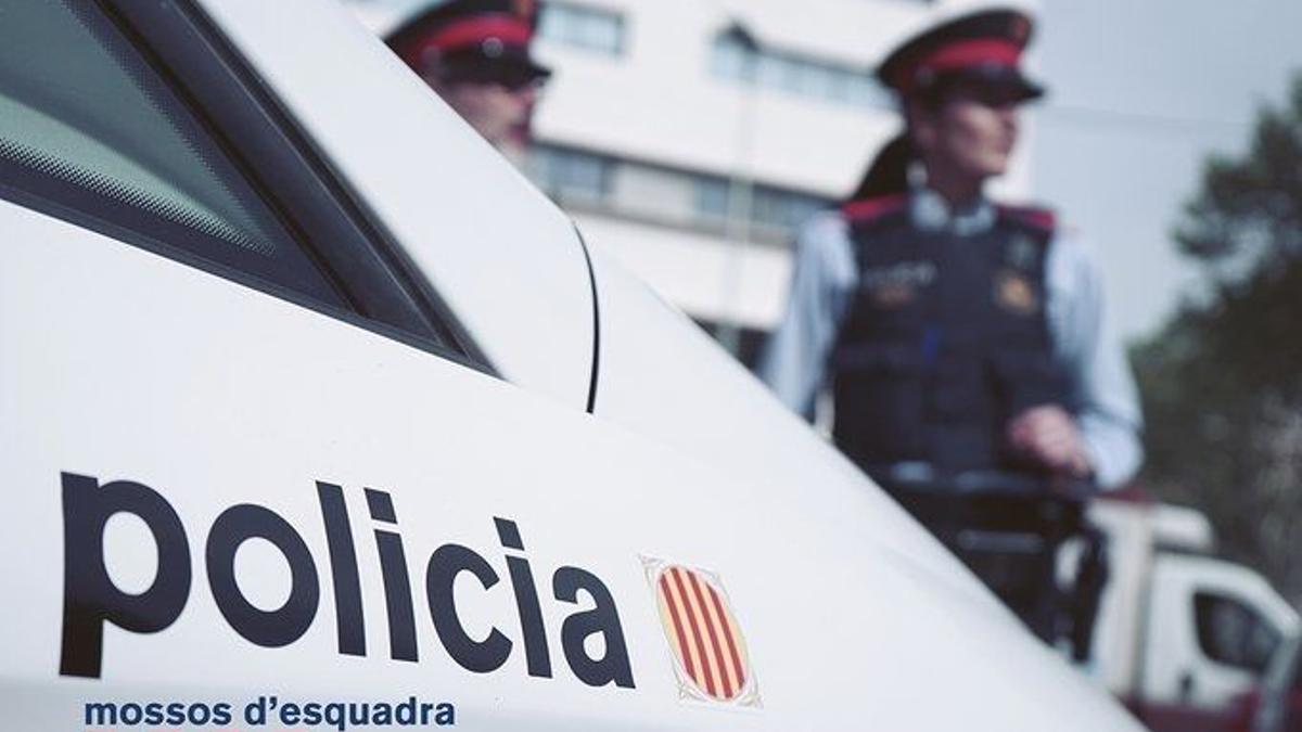 Agentes de los Mossos d'Esquadra junto a un vehículo policial.
