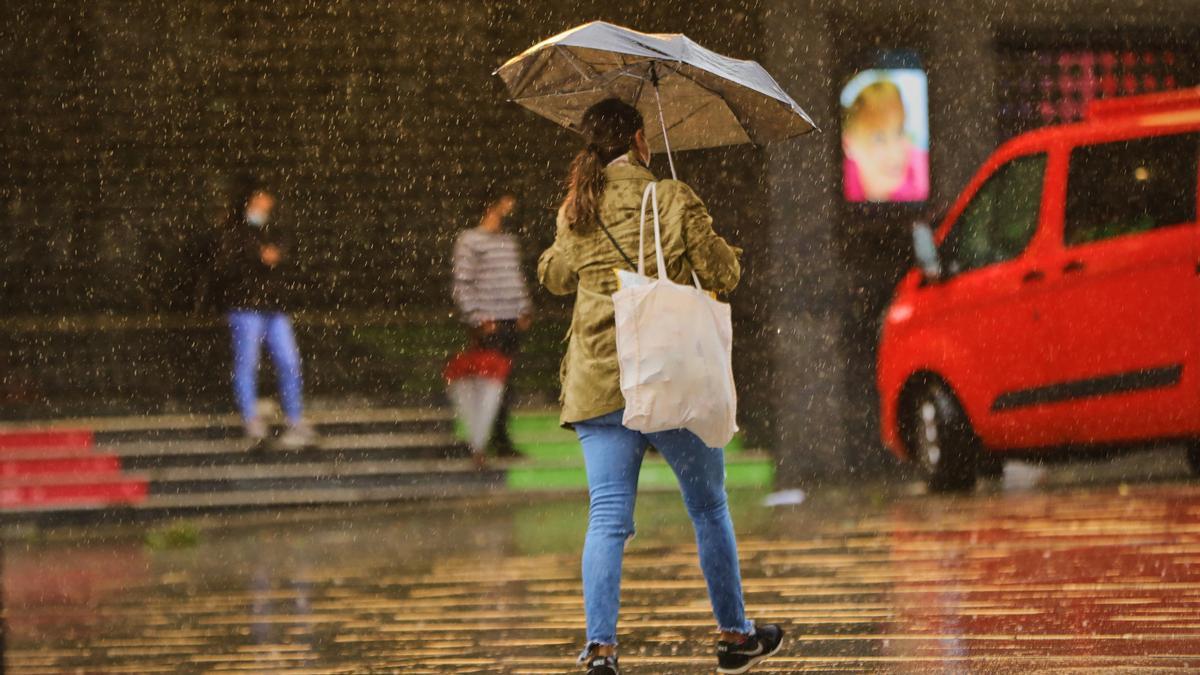Archivo - Una persona camina durante una jornada marcada por las lluvias