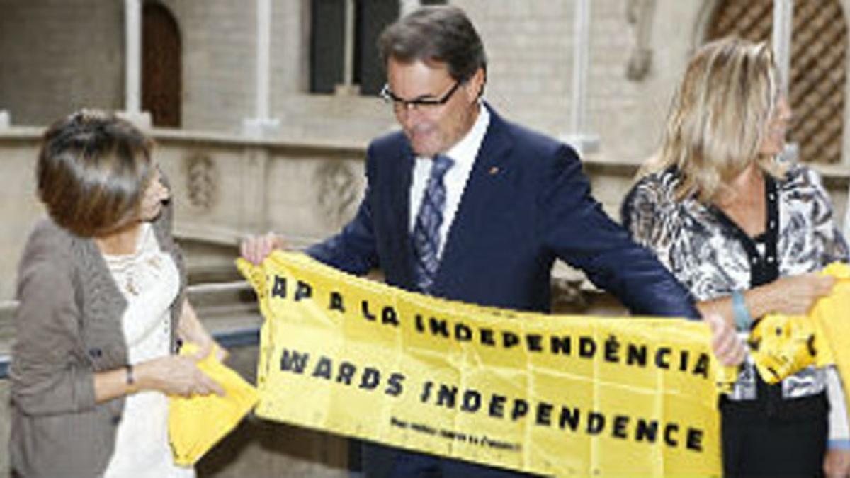 Artur Mas extiende uno de los obsequios de Carme Forcadell, presidenta de la ANC, este miércoles, en Barcelona.