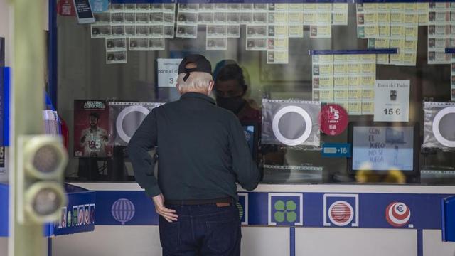 Dos personas compran lotería en una Administración.