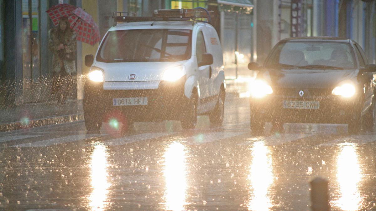 Dos vehículos circulan bajo la lluvia en Gandia.