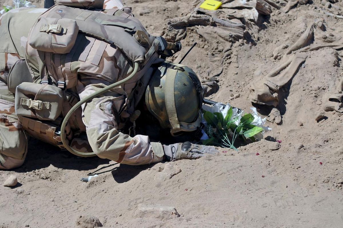 A soldier prays at a mass grave for Shi’ite soldiers from Camp Speicher who have been killed by Islamic State militants in the presidential compound of the former Iraqi president Saddam Hussein in Tikrit, Iraq April 6, 2015. REUTERS/Stringer/File Photo