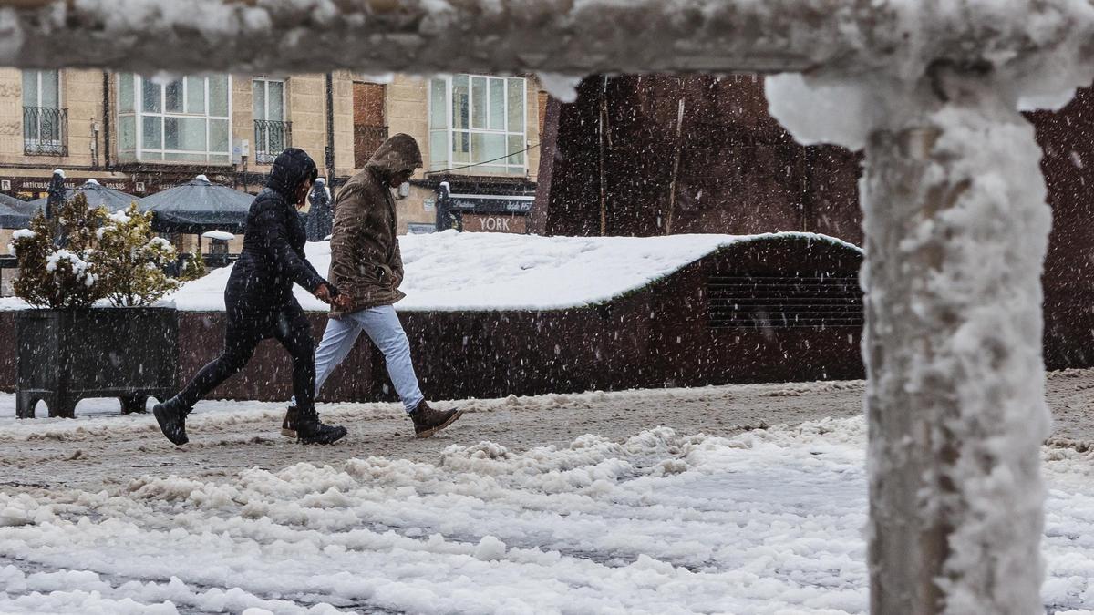 Dos personas caminan por una calle cubierta de nieve, en una imagen de archivo.