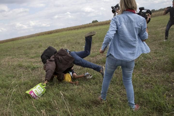 Una reportera húngara agrede a un refugiado que carga con su hijo.