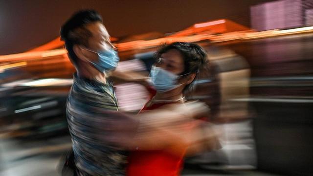 Una pareja baila con mascarillas en un parque junto al río Yangtsé, en Wuhan, localidad china donde se originó el coronavirus, el 27 de mayo