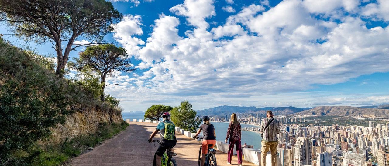 Turistas paseando y pedaleando por Sierra Helada. Al fondo Benidorm este diciembre