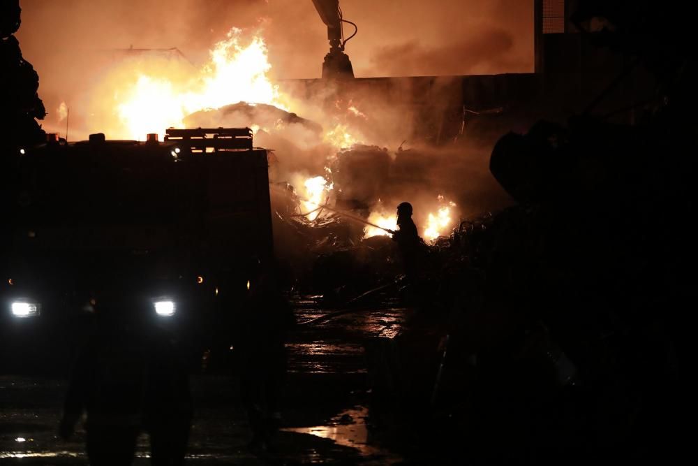 Labores de extinción del incendio de un desguace en Gijón