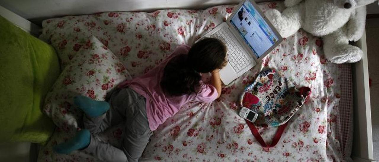 Una niña navega por la red con su portátil desde su cama. |   // DAVID CASTRO