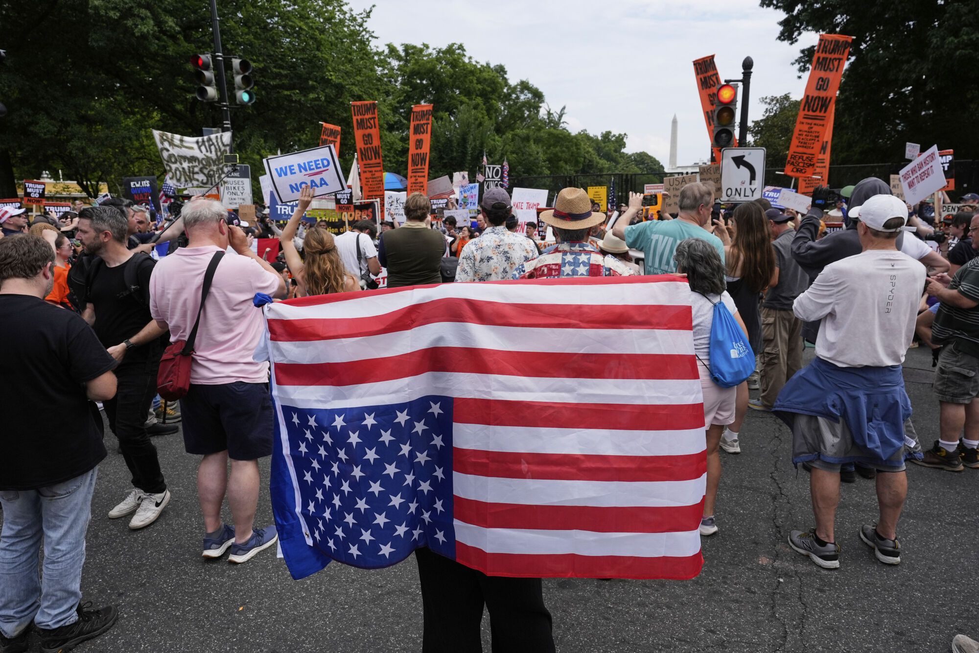 A demonstrator carries an American flag upside-down near the White House during a protest taking place on the day of a military parade commemorating the Army's 250th anniversary, coinciding with President Donald Trump's 79th birthday, Saturday, June 14, 2025, in Washington. (AP Photo/Alex Brandon)