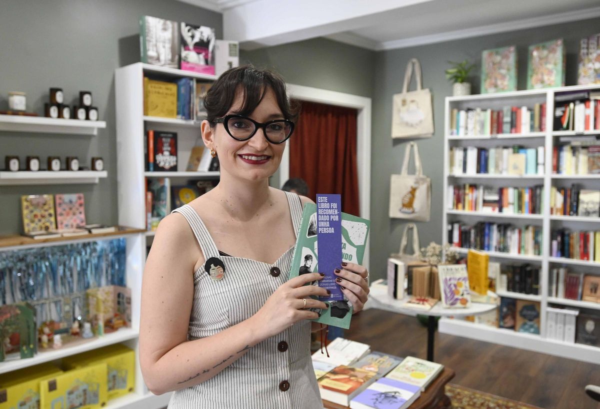 Tania Lago Míguez, dona da libraría Rosalía e Compañía, amosa un marcapáxinas da campaña que pon en valor o traballo dos libreiros.