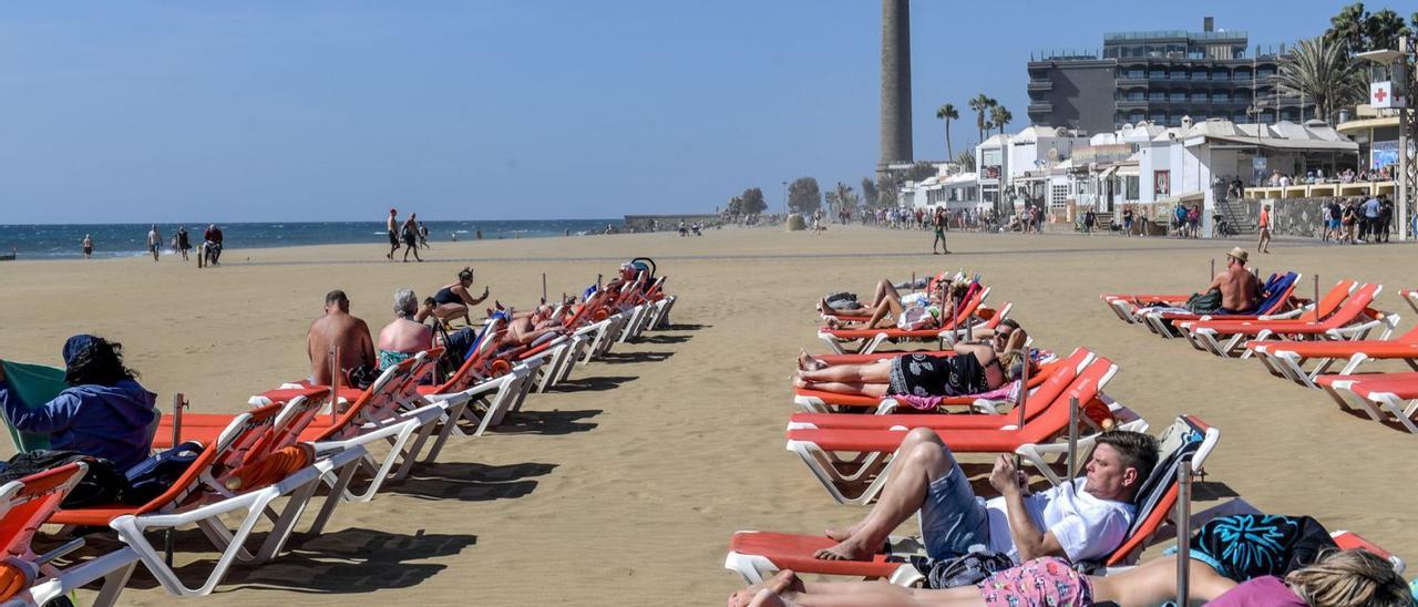 Turistas en hamacas en una imagen reciente de la playa de Maspalomas. Al fondo algunas terrazas cerca del Faro. | | J.C. CASTRO