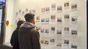 Dos jóvenes miran las ofertas de pisos en alquiler en una inmobiliaria de A Coruña. MERCADO INMOBILIARIO. INMOBILIARIAS. VIVIENDA. VENTA. ALQUILER DE PISOS