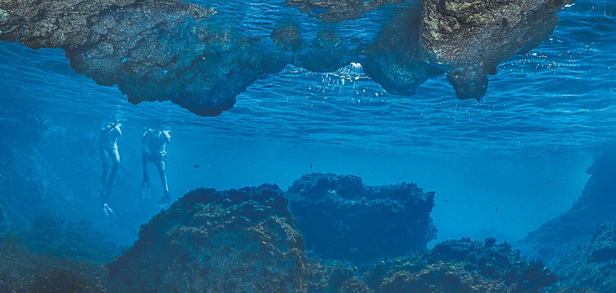 Unos bañistas fotografiados en la entrada de una cueva submarina en Benirràs.